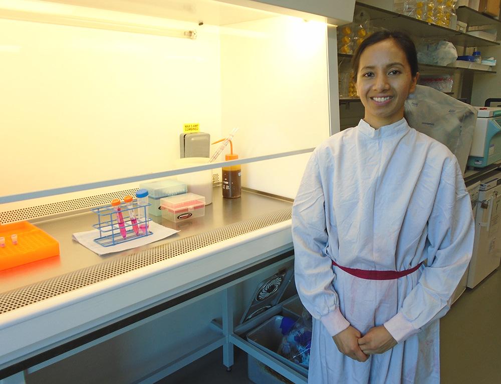 Amanda Corla stood in a lab coat next to a hooded cabinet