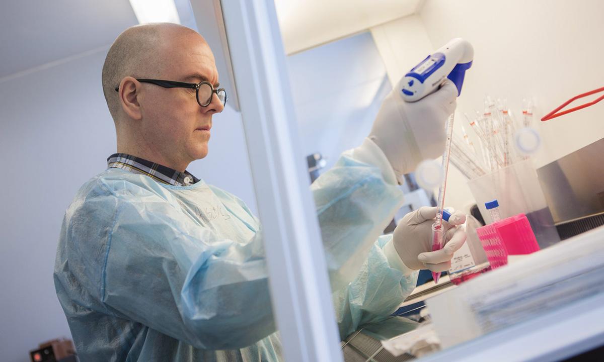 Michael Jarvis in plastic gown pipetting