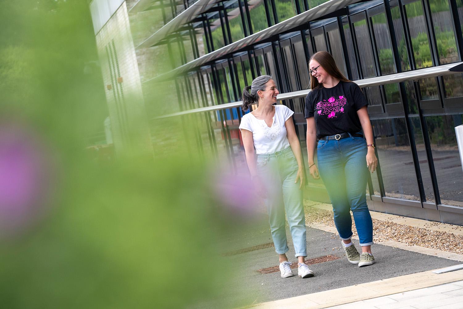 Two people walking by a building talking