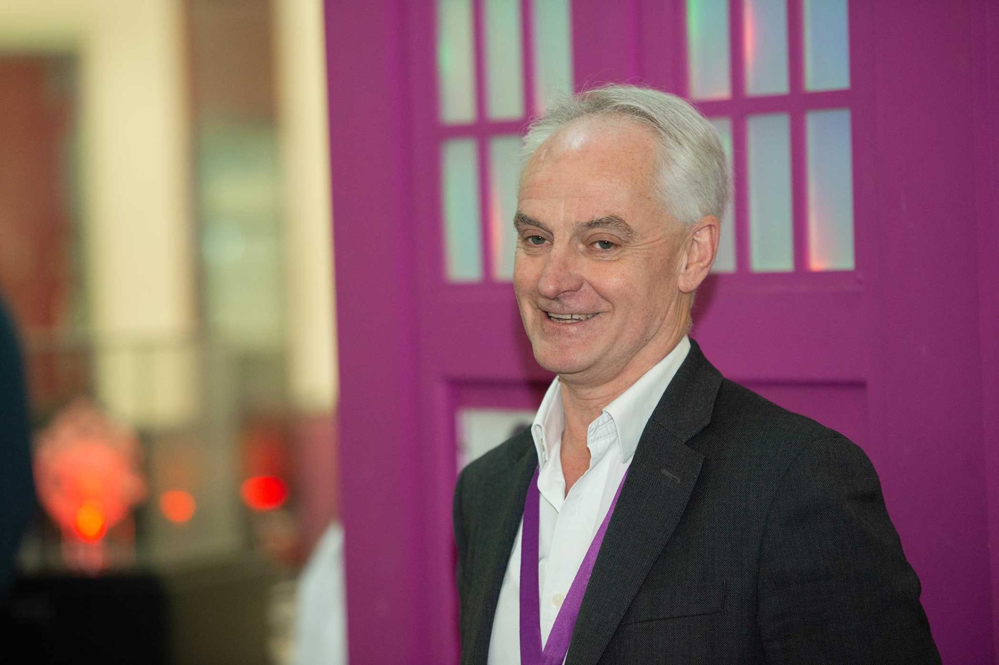 Professor Bryan Charleston smiling in grey suit with white shirt