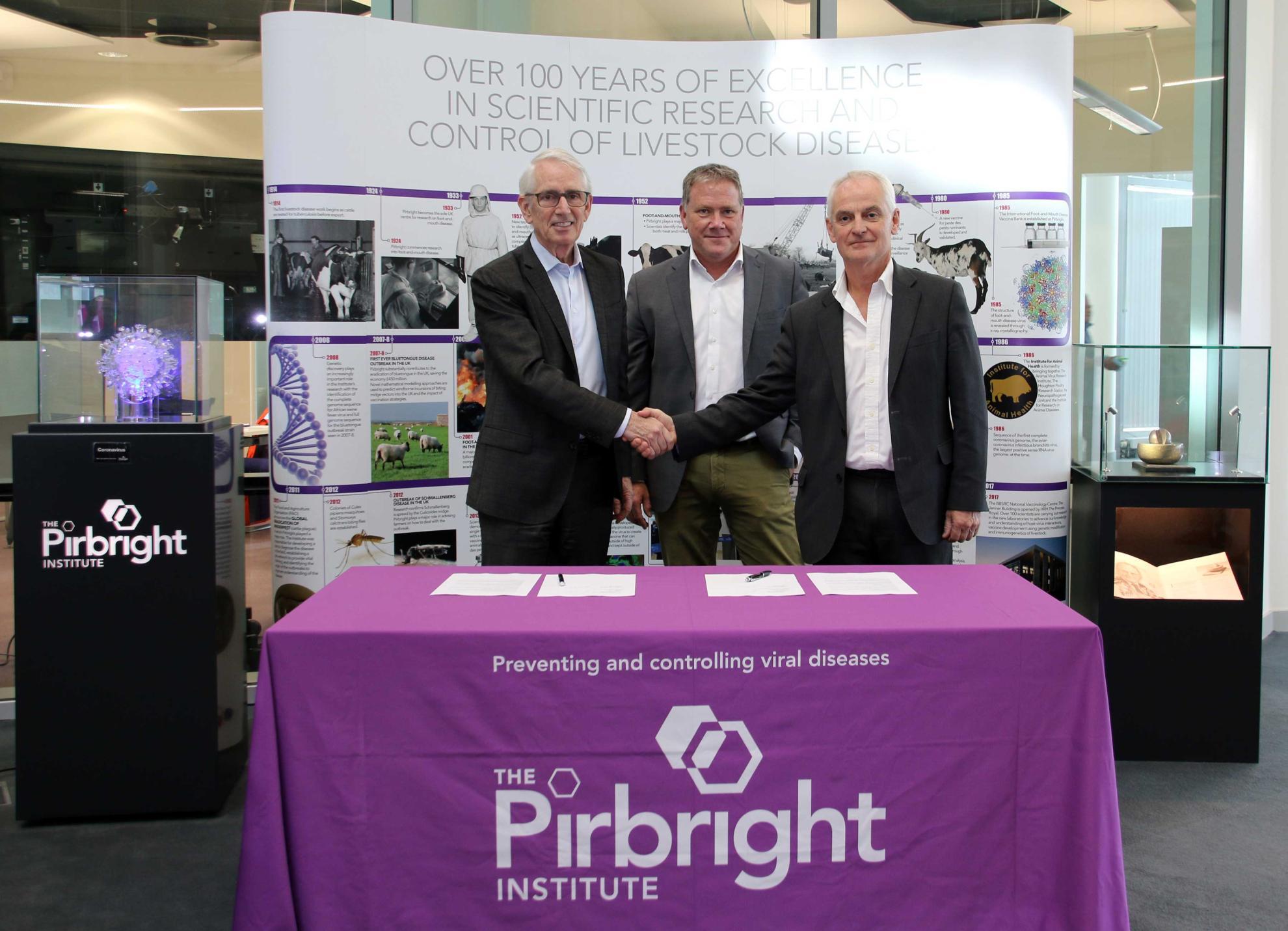 Professor Bryan Charleston and Peter Stoicheff shakes hands, with Dr. Volker Gerdts stood behind them. 