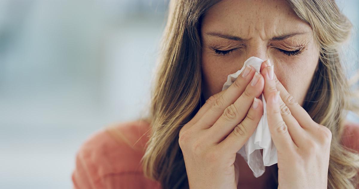 Lady sneezing into tissue